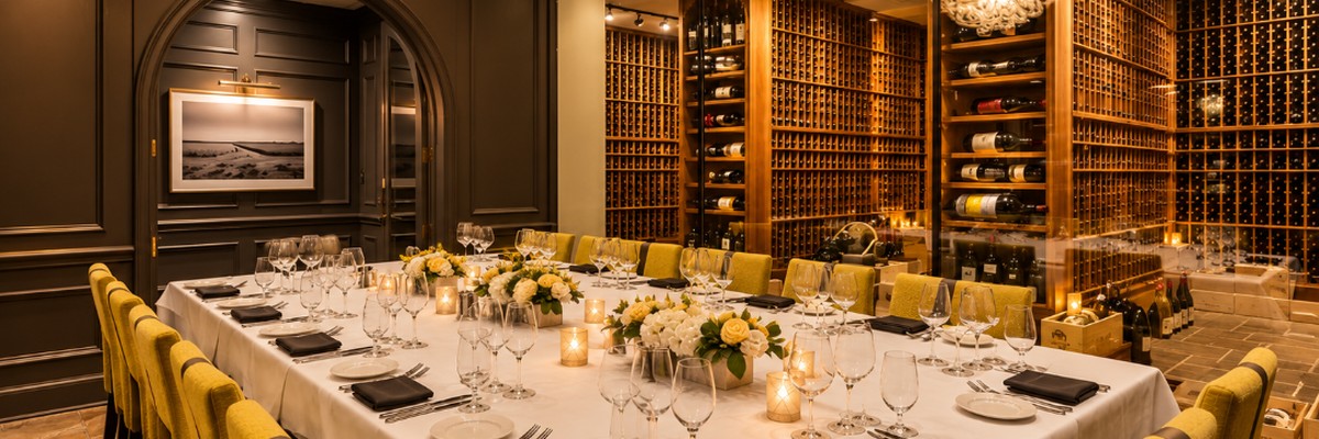 Private dining room at White Glove Steakhouse set for an intimate wedding celebration, surrounded by a glass-walled wine cellar